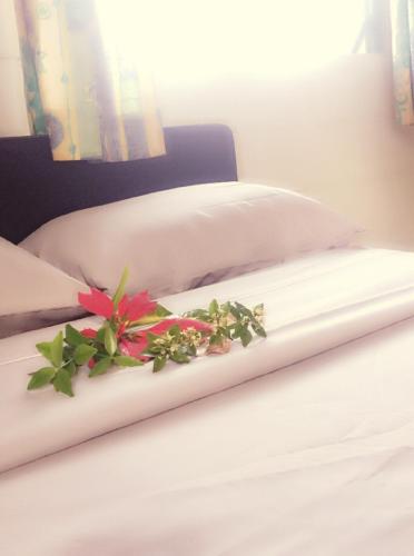 a white bed with a flower decoration on it at Green Lodge Holiday Homes in Nuku‘alofa