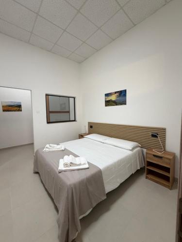 a bedroom with a large bed with a table and a lamp at Guest House Colfiorito by Ospitaci in Colfiorito