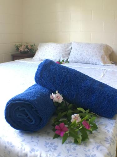 a bed with blue towels and flowers on it at Green Lodge Holiday Homes in Nuku‘alofa