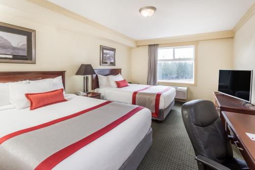 a hotel room with two beds and a desk at Ramada by Wyndham Hinton in Hinton