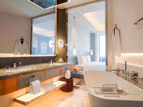 a bathroom with a tub and a bedroom with a bed at Sofitel Haikou in Haikou