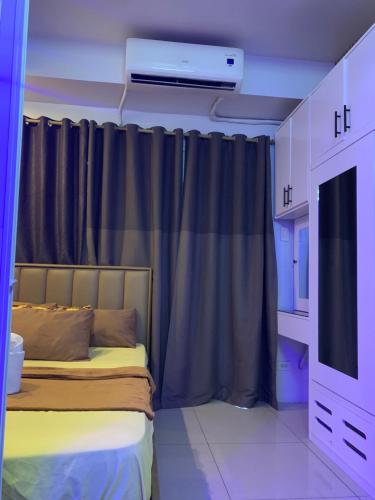 a room with a bed with a curtain and a tv at MOA Prime Staycation Sea Residences in Manila