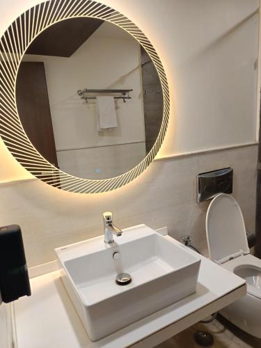 a bathroom with a white sink and a mirror at Hotel Tushar Elegant in Ghaziabad