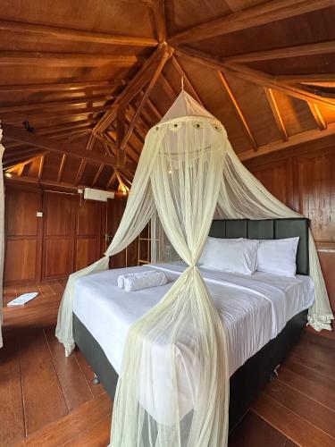 a bed with mosquito netting in a room at Kelapa Sunrise Villa in Silebeng