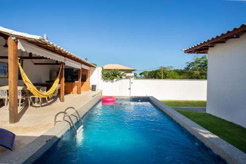 a swimming pool with a hammock in a backyard at QUINTAL DE BÚZIOS- casa com piscina e 3 suítes completas in Búzios
