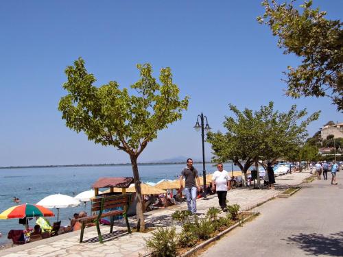 two men walking down a sidewalk next to the water at Delfini Hotel in Menídion