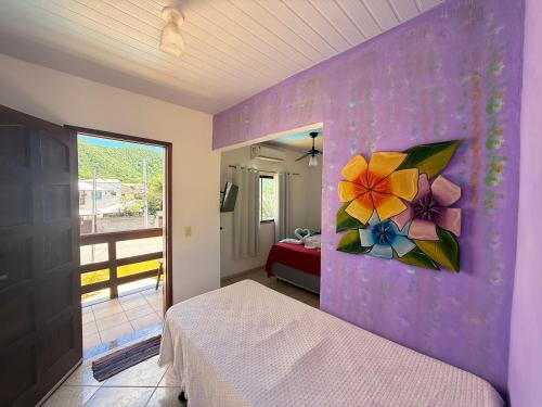 ein Schlafzimmer mit einem Bett und einem Gemälde an der Wand in der Unterkunft Pousada Luz e Brilho Aluguel Temporada in Búzios