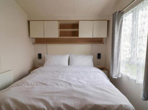 a white bed in a room with a window at Caravan CP10 in Prestatyn