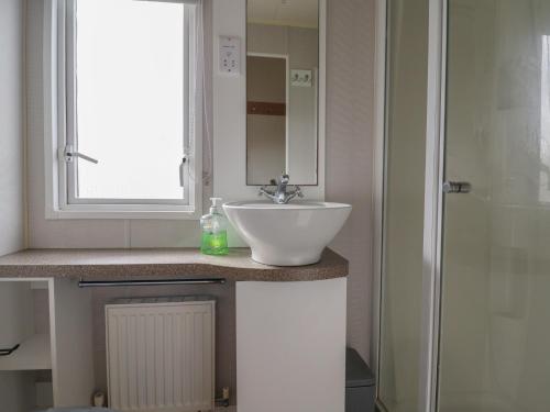 a bathroom with a white sink and a shower at Caravan CP10 in Prestatyn