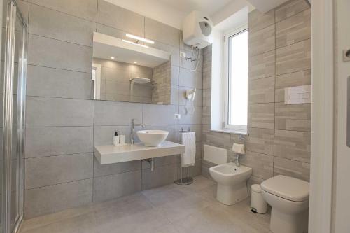 a bathroom with a sink and a toilet and a mirror at B&B Sikelia Suite in Agrigento