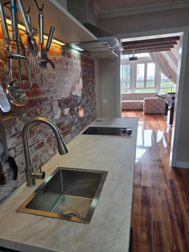 a kitchen with a sink and a brick wall at Loft Linda in Sylt