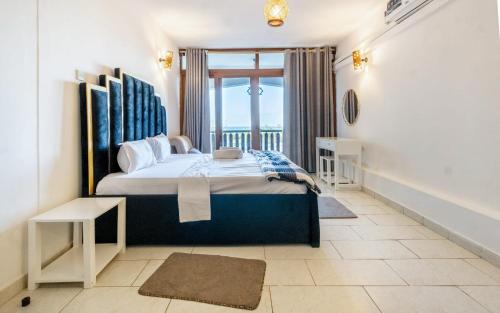 a bedroom with a large bed and a window at Diani Beachfront by Bstan in Diani Beach