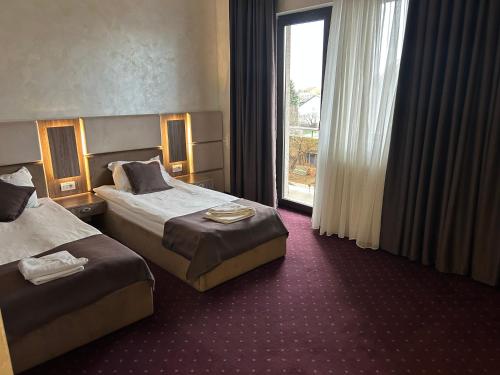 ein Hotelzimmer mit zwei Betten und einem Fenster in der Unterkunft Le Mer in Afumaţi