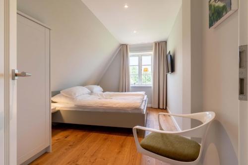 a small bedroom with a bed and a chair at Haus an der Koppel in Borgsum