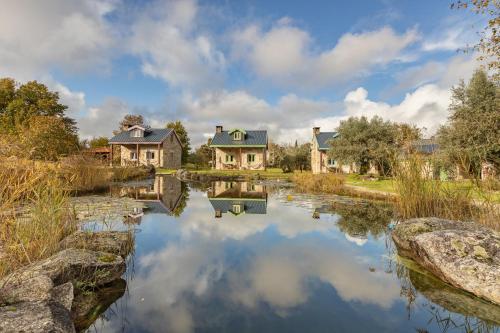 a home with a pond in front of some houses at Chão do Rio - Turismo de Aldeia - Serra da Estrela in Seia