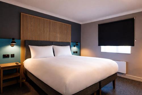 a bedroom with a large white bed with a large window at Village Hotel Coventry in Coventry