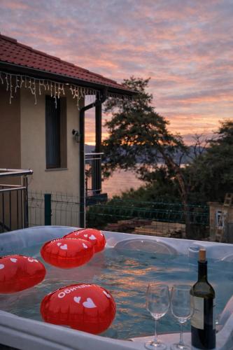 a hot tub with wine glasses and a bottle of wine at Къща за гости "СЛАВЕНА" in Dospat