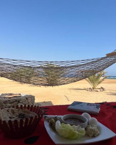 a plate of food and a hammock on the beach at Heaven Dune Camp in Nuweiba