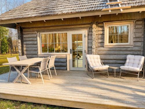 a wooden deck with a table and chairs in front of a cabin at Liedaga 24 in Tūja