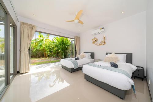 a bedroom with two beds and a large window at Nivara Pool Villa - Rawai in Rawai Beach