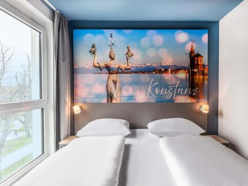 two beds in a room with a poster on the wall at B&B Hotel Konstanz in Konstanz