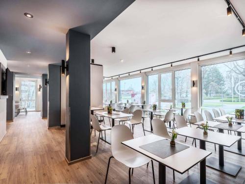 a restaurant with tables and chairs and large windows at B&B Hotel Konstanz in Konstanz