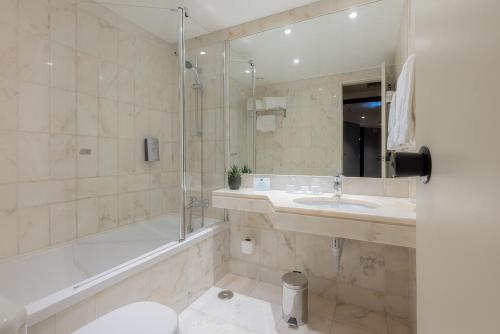 a bathroom with a tub and a sink and a shower at Hotel Dom Carlos Park in Lisbon