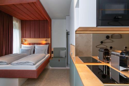 une petite chambre avec un lit et une cuisine dans l'établissement Cocoon München Theresienwiese, à Munich