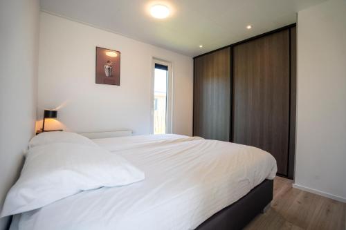 a bedroom with a large white bed and a window at Vakantiepark Lemmer in Lemmer