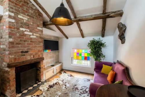 a living room with a brick fireplace and a purple couch at Beamed Village Apartment with Fireplace and Private Terrace, Castle Donington in Castle Donington