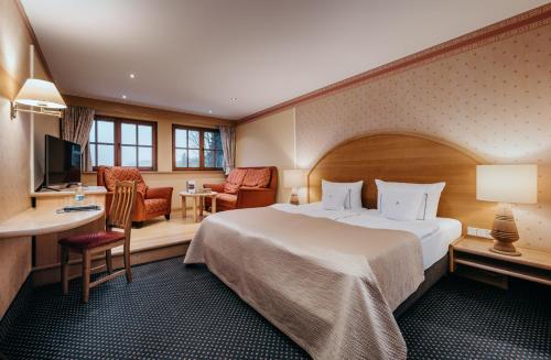 a hotel room with a large bed and a desk at Waldhaus Ohlenbach in Schmallenberg