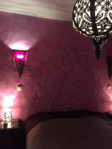 a bedroom with purple walls and chandeliers at Gîte de Corbion une envie d'Ailleurs 6personnes et le Pt Bonheur 2 personnes in Leignon