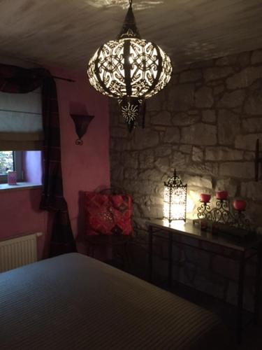 a bedroom with a chandelier and a stone wall at Gîte de Corbion une envie d'Ailleurs 6personnes et le Pt Bonheur 2 personnes in Leignon