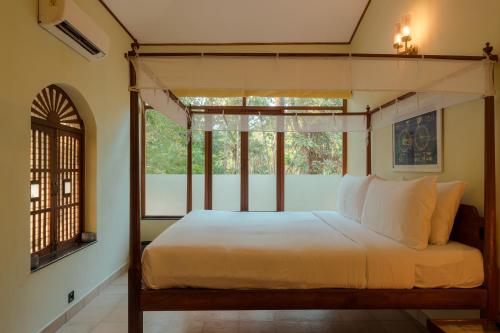 a bedroom with a canopy bed and a window at Botanique Goa in Assagao