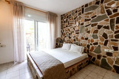 a bedroom with a stone wall with a bed and a window at Stefanidis studios in Stavros