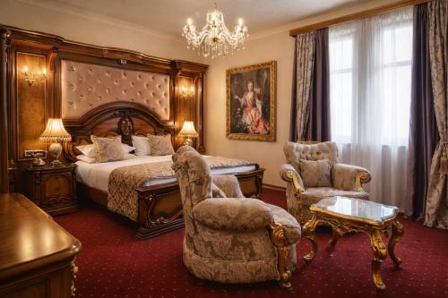 a bedroom with a bed and chairs and a chandelier at Premier Prezident Garni Hotel and Spa in Sremski Karlovci