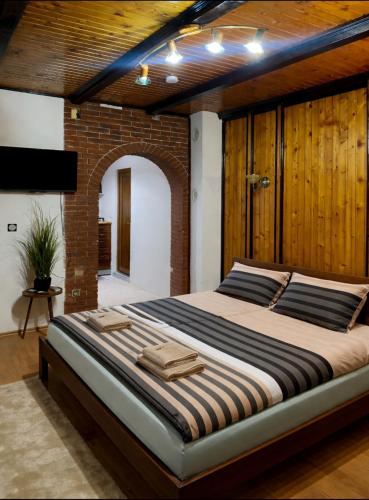 a large bed in a room with a brick wall at Serana Stays Modern Rooms with Private Bathroom, Free WiFi & Parking, Central Pejë in Peje