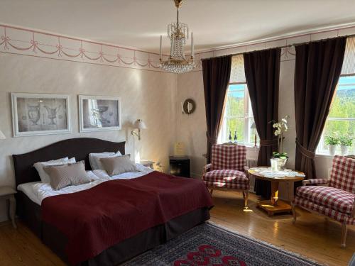 a bedroom with a bed and two chairs and a table at Bångbro Herrgård in Kopparberg