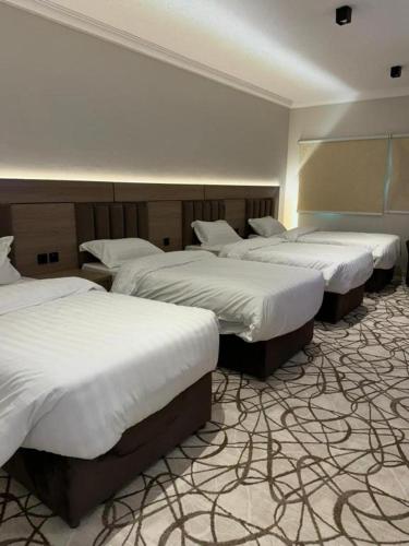 a group of four beds in a room at Dvina Hotel دفينا in Tabuk