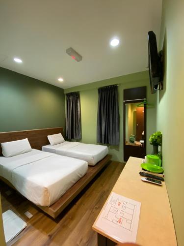 two beds in a room with green walls and a desk at Perdana Hotel Labuan in Labuan