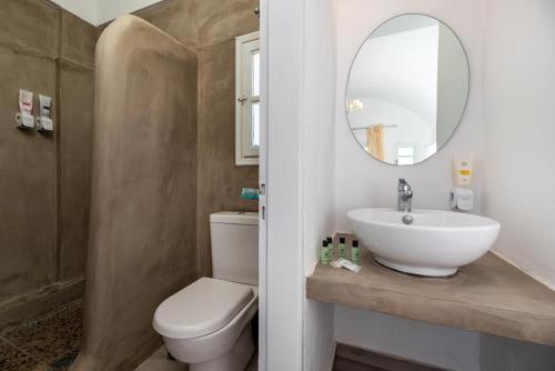 a bathroom with a sink and a toilet and a mirror at Maistros Village Santorini - Anamar Collection in Karterados