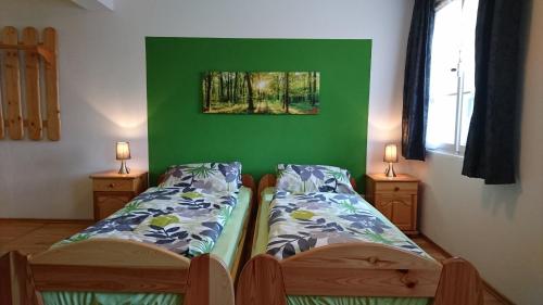 two beds in a room with a green wall at Hotel Garni Forsthaus Ruhpolding in Ruhpolding
