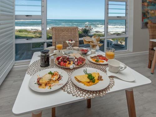 a table with plates of breakfast food and the ocean at Absolute Ocean Boutique Guesthouse in Hermanus
