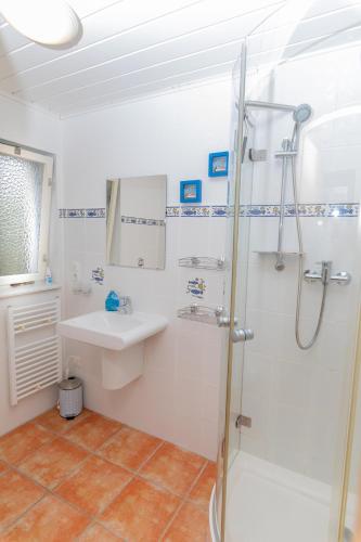 a white bathroom with a sink and a shower at Hundeparadies "Bodden Paradise Cottage" in Pruchten
