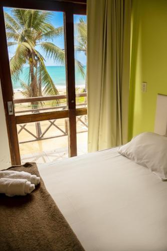a bedroom with a bed with a view of the beach at Pousada Maraca Beach in Porto De Galinhas