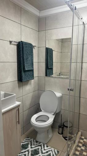 a bathroom with a toilet and a shower with green towels at The Swiss Garden in Midrand