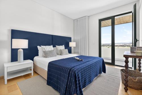 a bedroom with a blue and white bed and a window at Aquamar Pro 402 in Quarteira