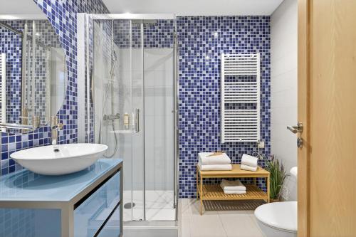 a bathroom with a sink and a shower with blue tiles at Aquamar Pro 402 in Quarteira