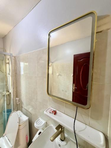 a bathroom with a mirror and a sink and a toilet at James Hotel & Apartments in Juba
