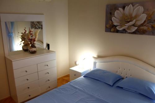 a bedroom with a bed and a dresser with a flower painting at Amigo Apartment in Mostar